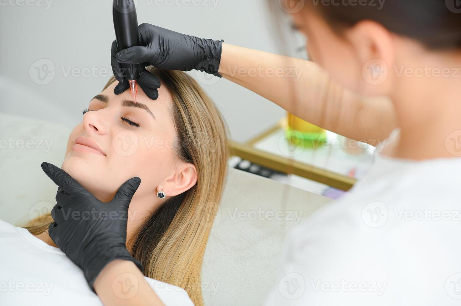 Young woman during procedure of permanent eyebrow makeup photo
