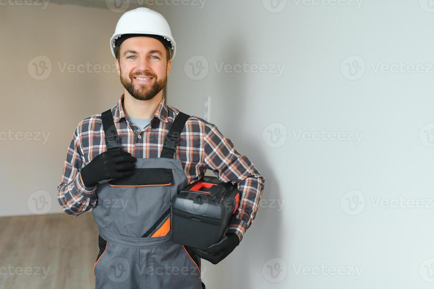 Portrait of a confident repairman with beard standing in empty apartment photo
