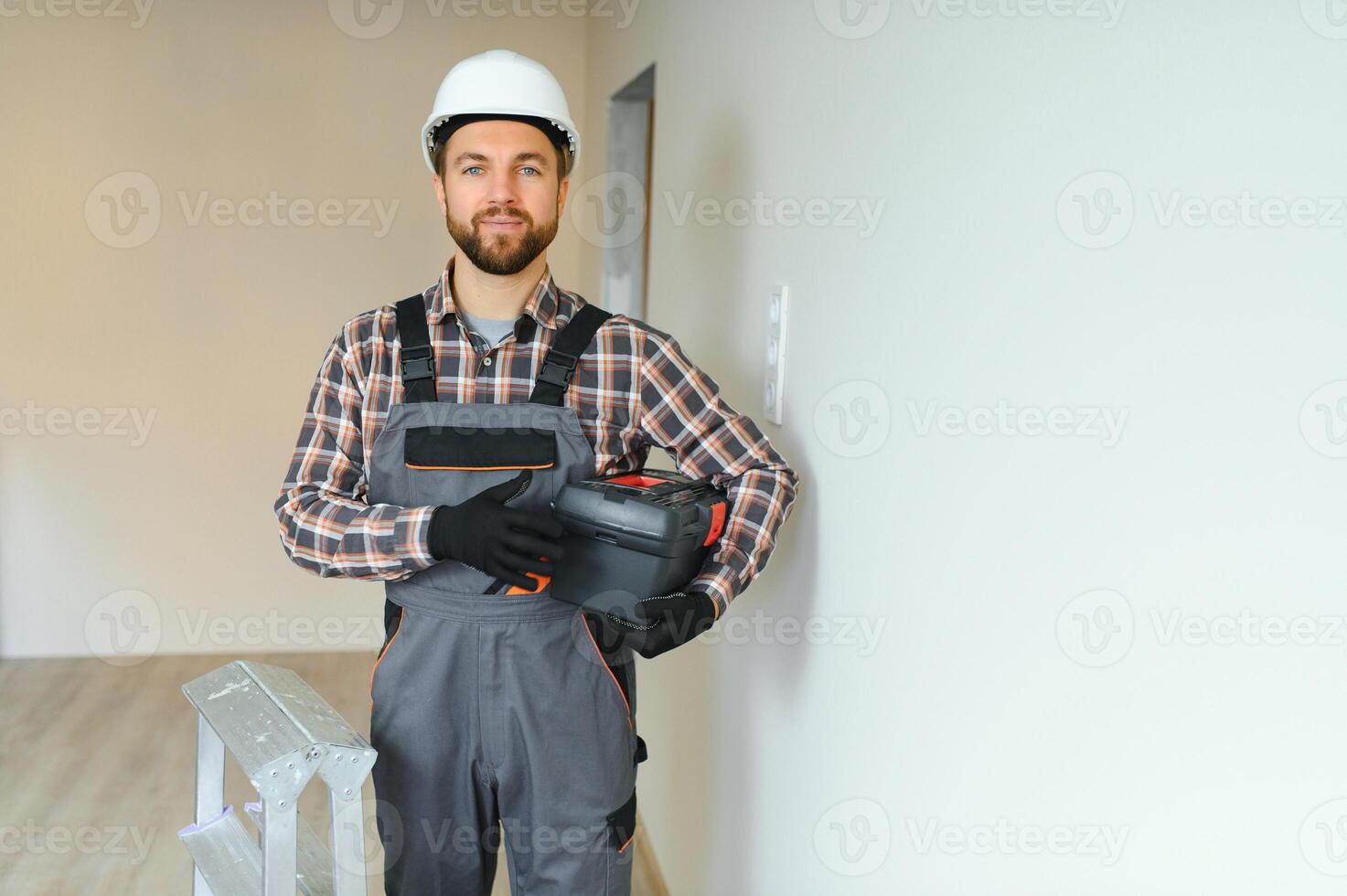 Portrait of a confident repairman with beard standing in empty apartment photo