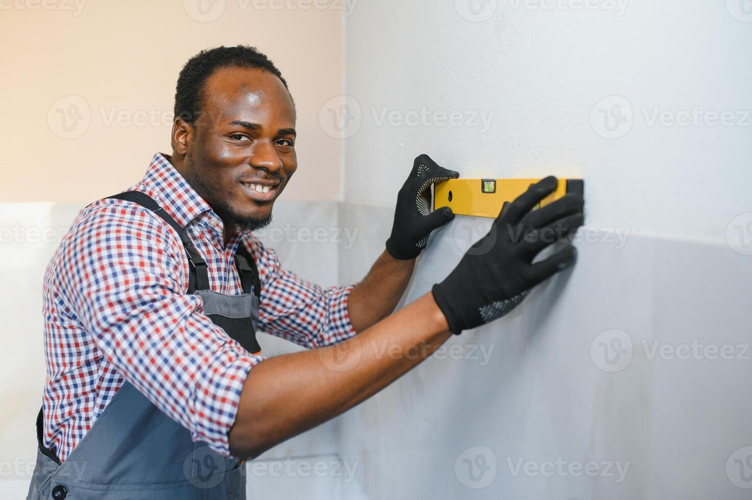 African American Worker installing wall tile with vacuum holder indoors photo