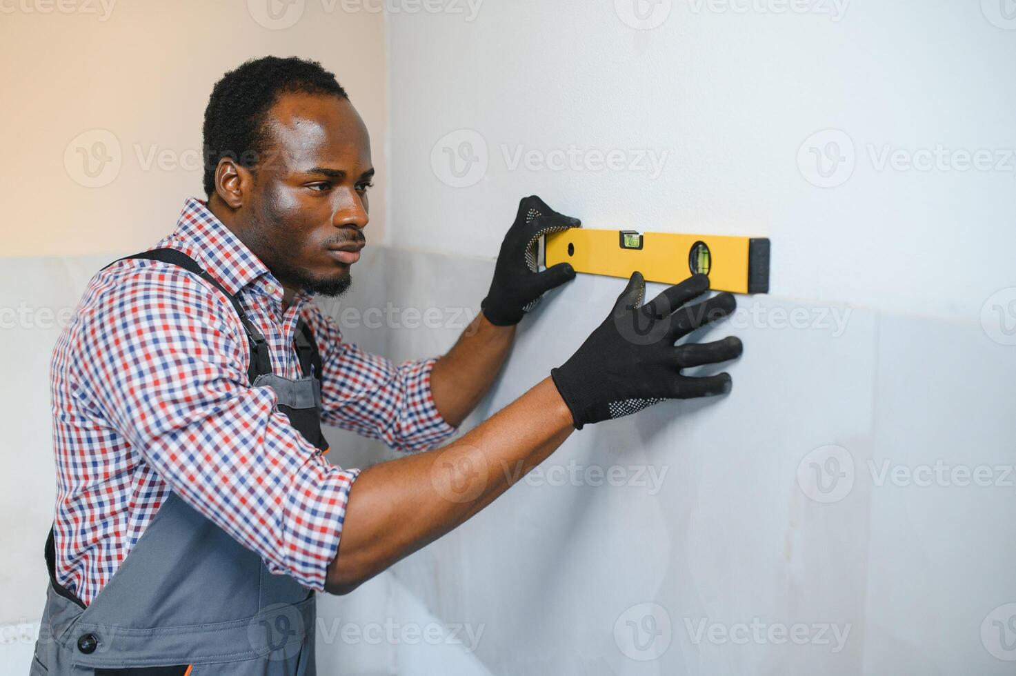 African American Worker installing wall tile with vacuum holder indoors photo