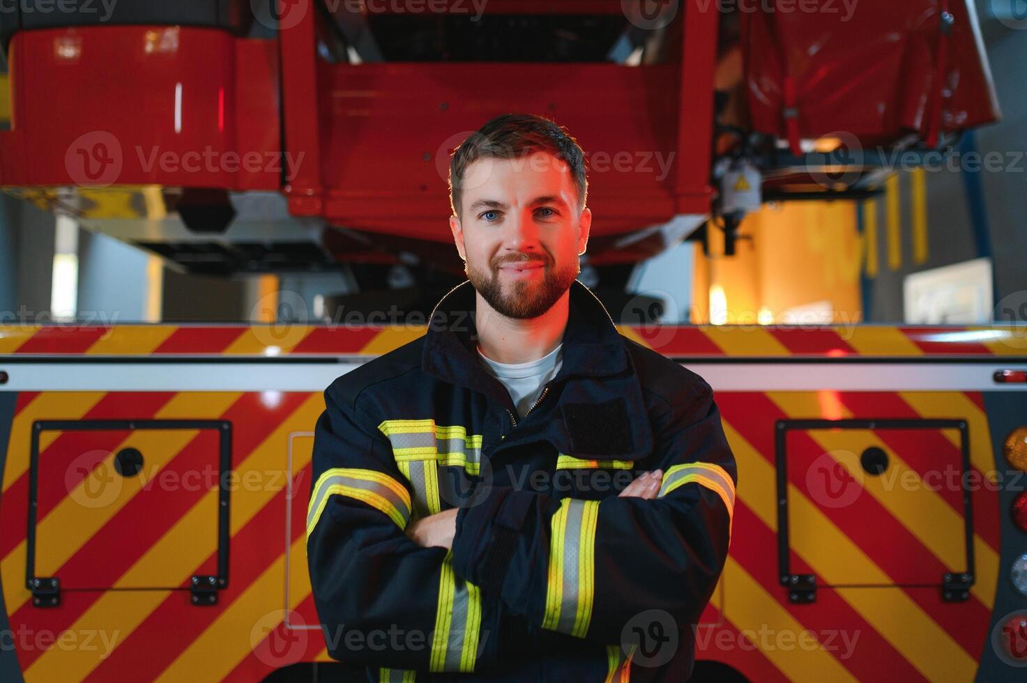 Firefighter in uniform and helmet near fire engine photo