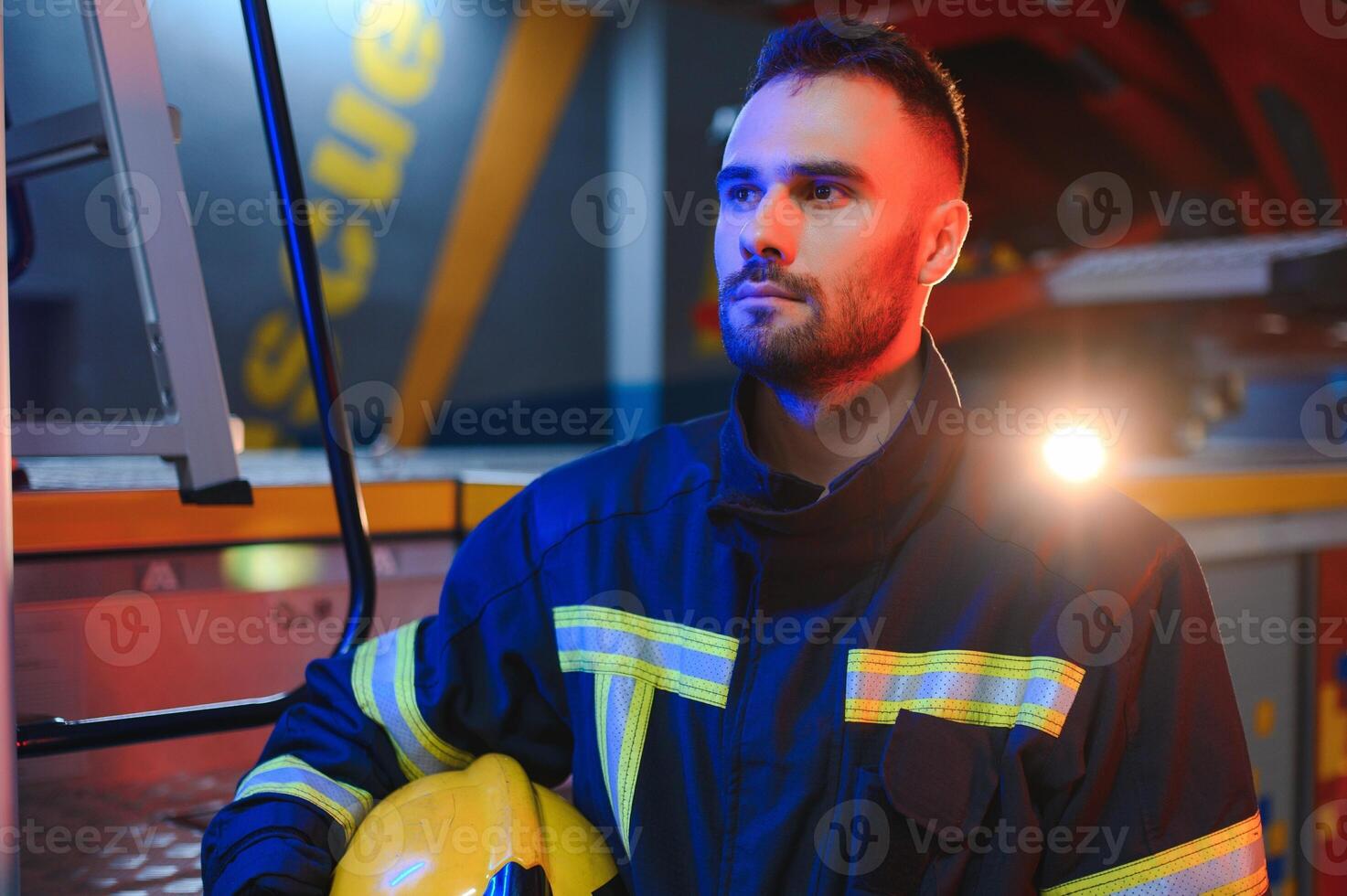 fireman in protective uniform standing near fire engine on station photo