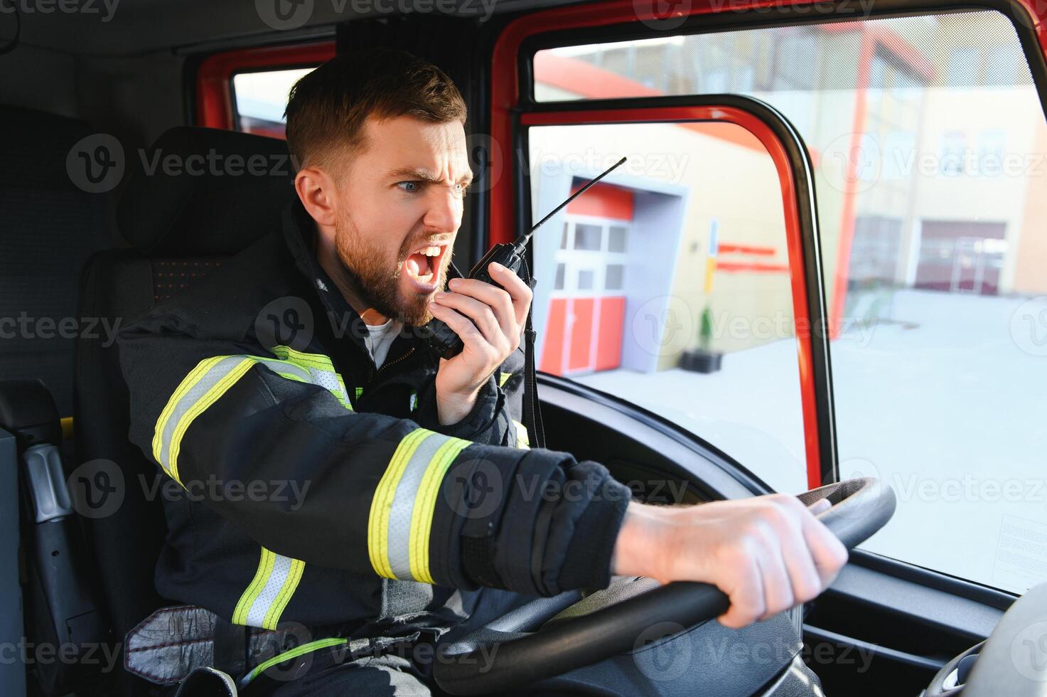 Side view of firefighter in protective uniform driving fire engine photo