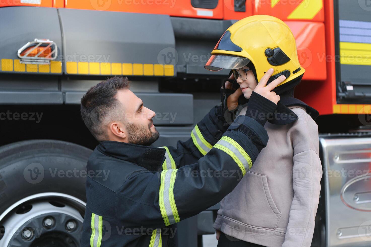 A firefighter take a little child boy to save him. Fire engine car on background photo