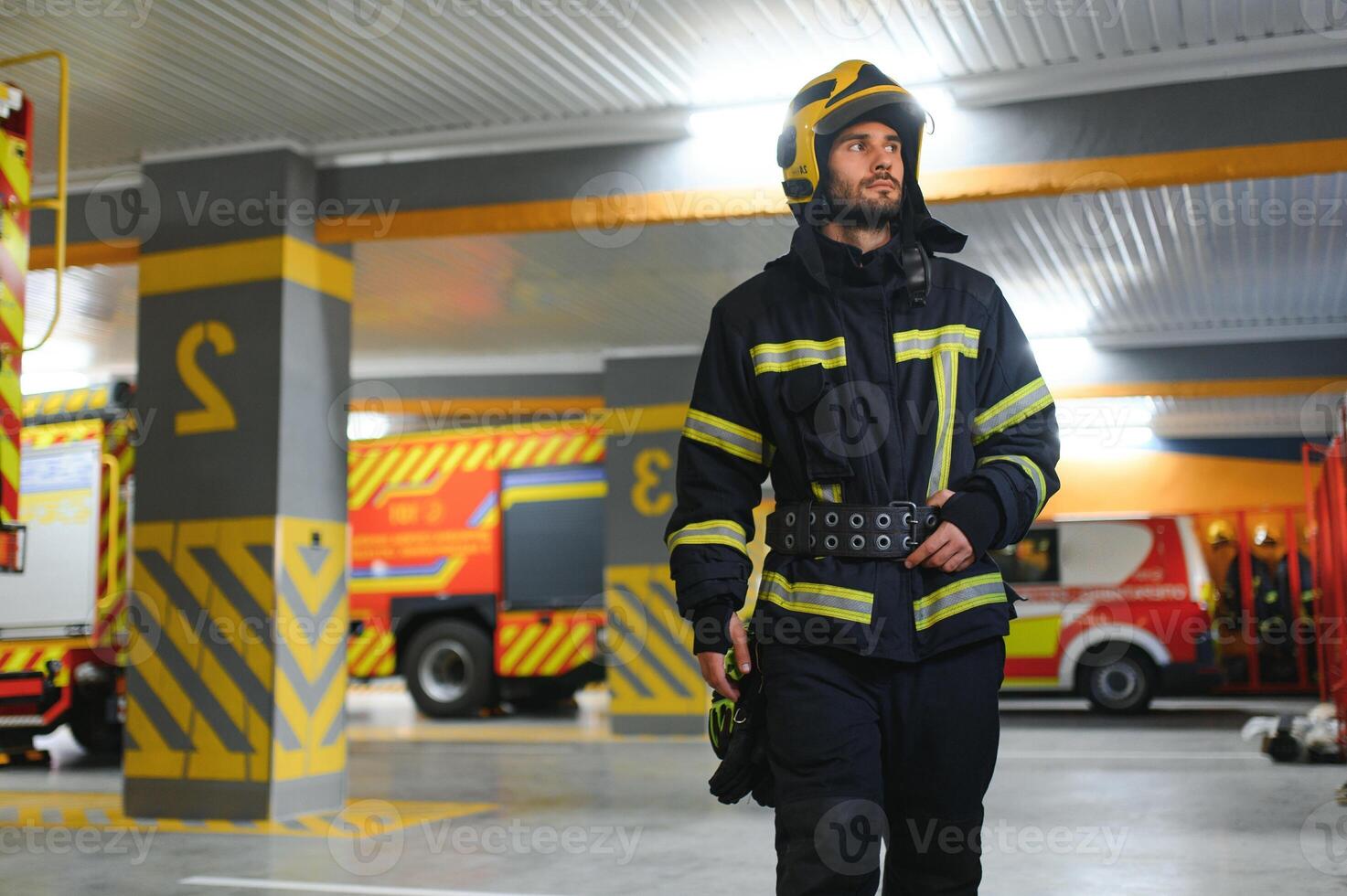 Fireman wearing protective uniform standing in fire department at fire station photo