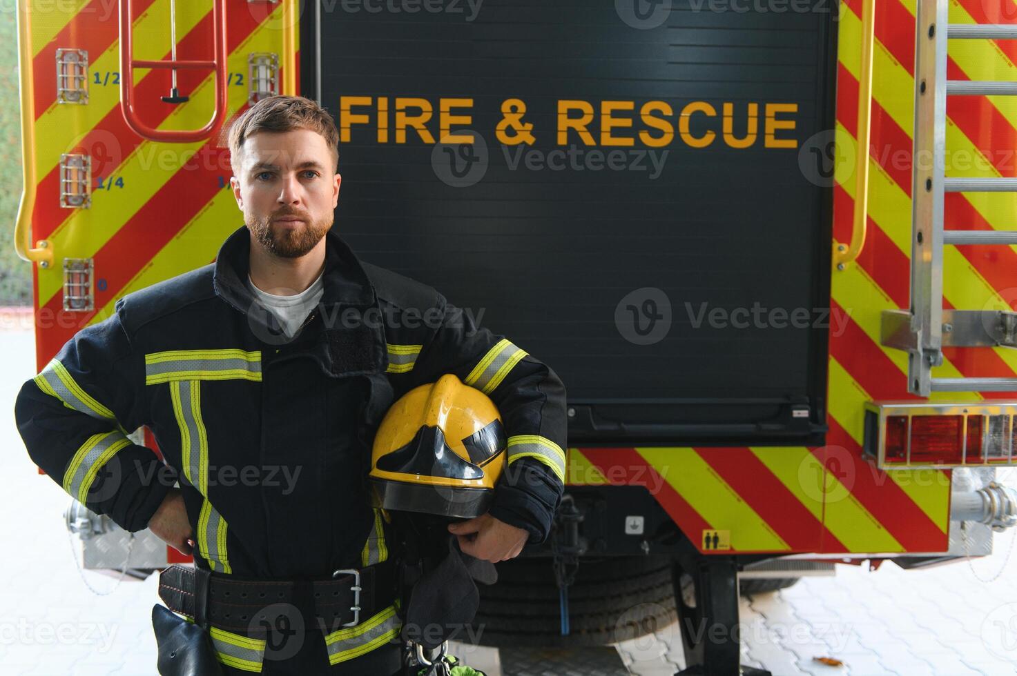 Firefighter in uniform and helmet near fire engine photo
