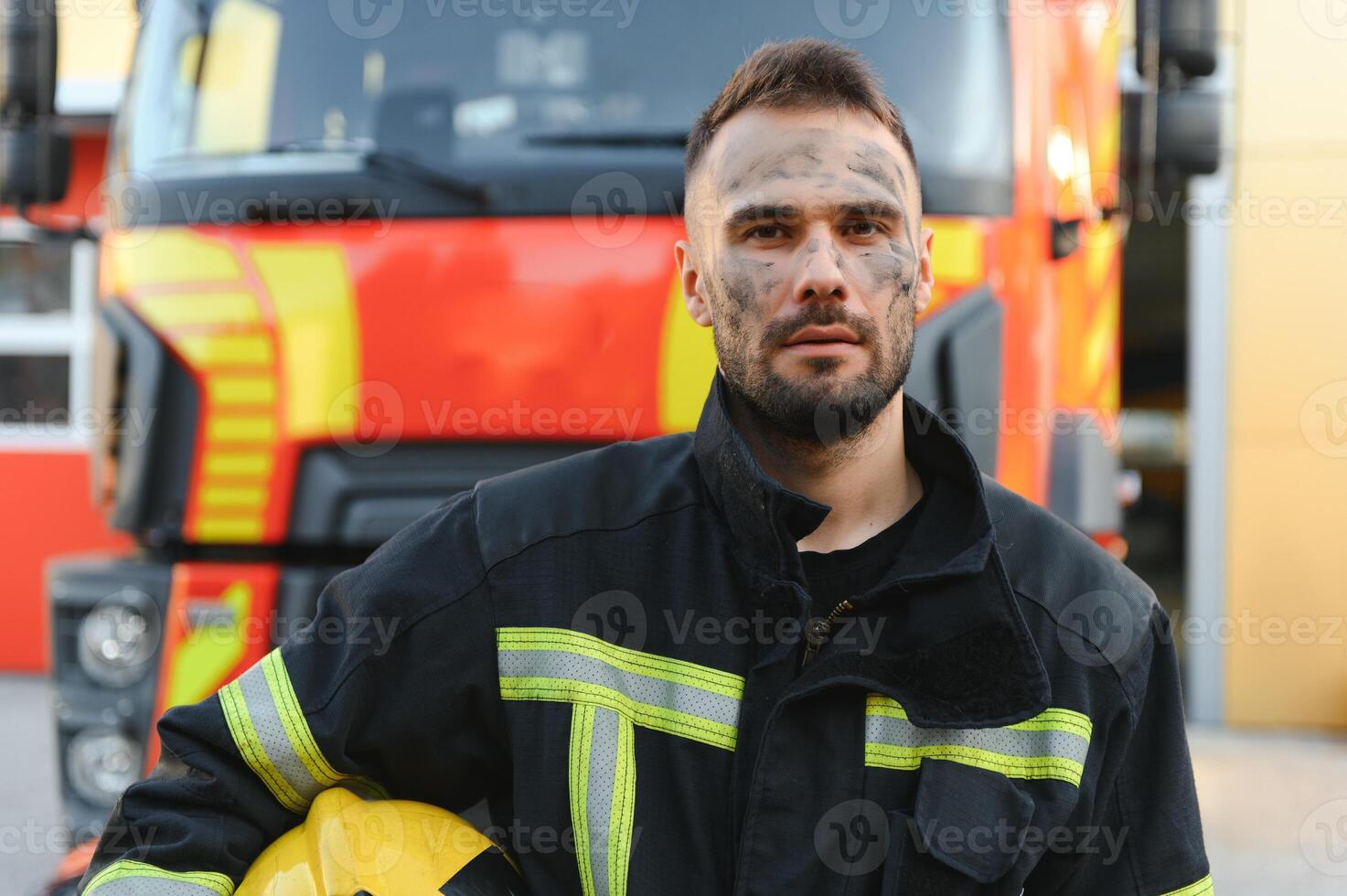 fireman in protective uniform standing near fire engine on station photo