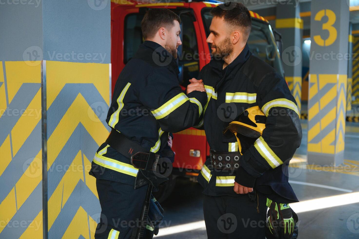 Group of firefighters at the emergency vehicle in the fire station photo