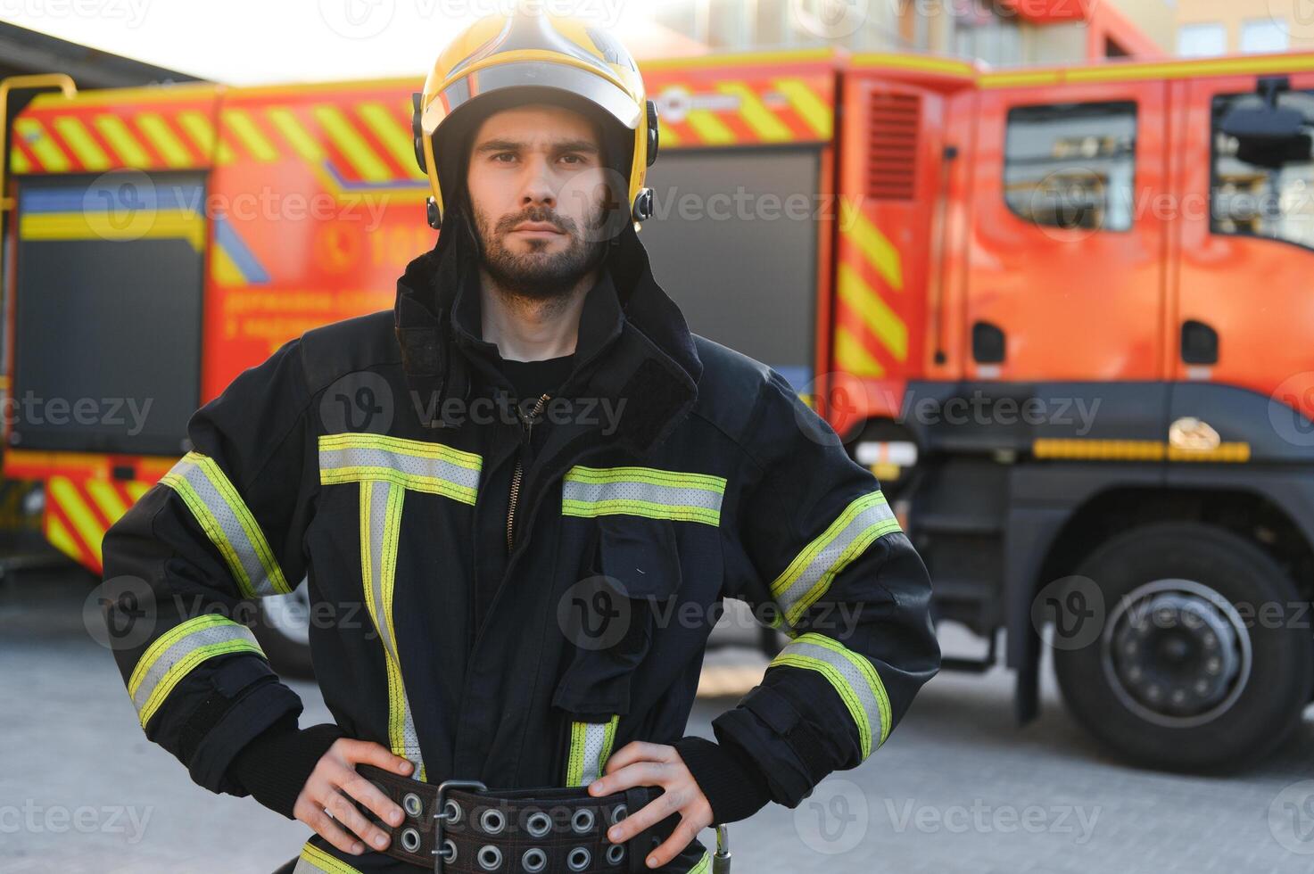 fireman in protective uniform standing near fire engine on station photo