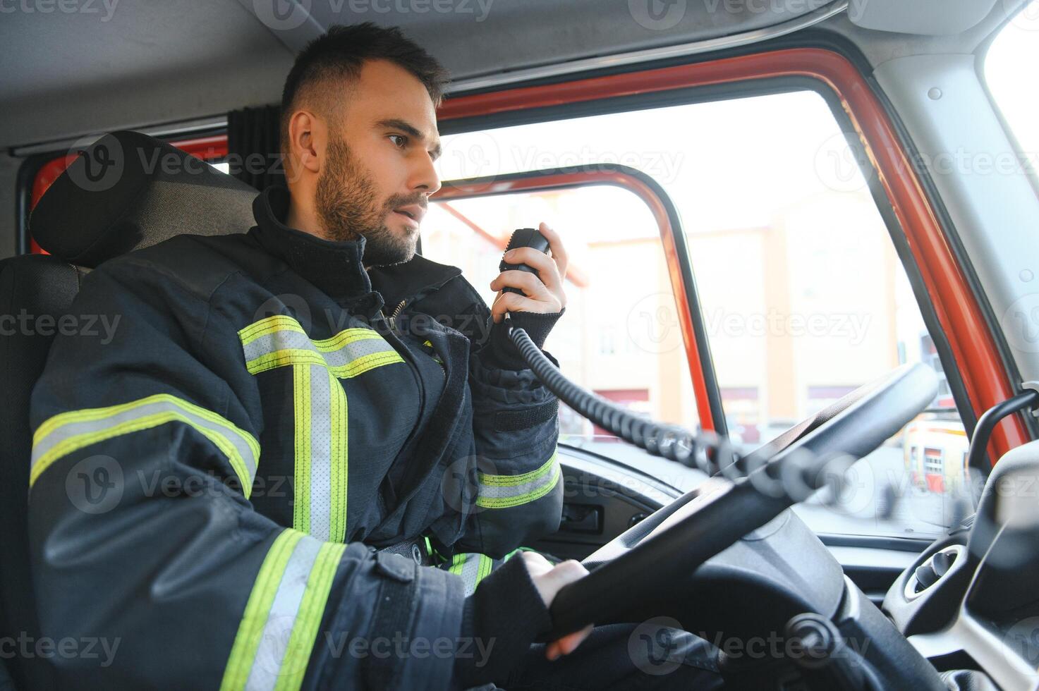 Side view of firefighter in protective uniform driving fire engine photo