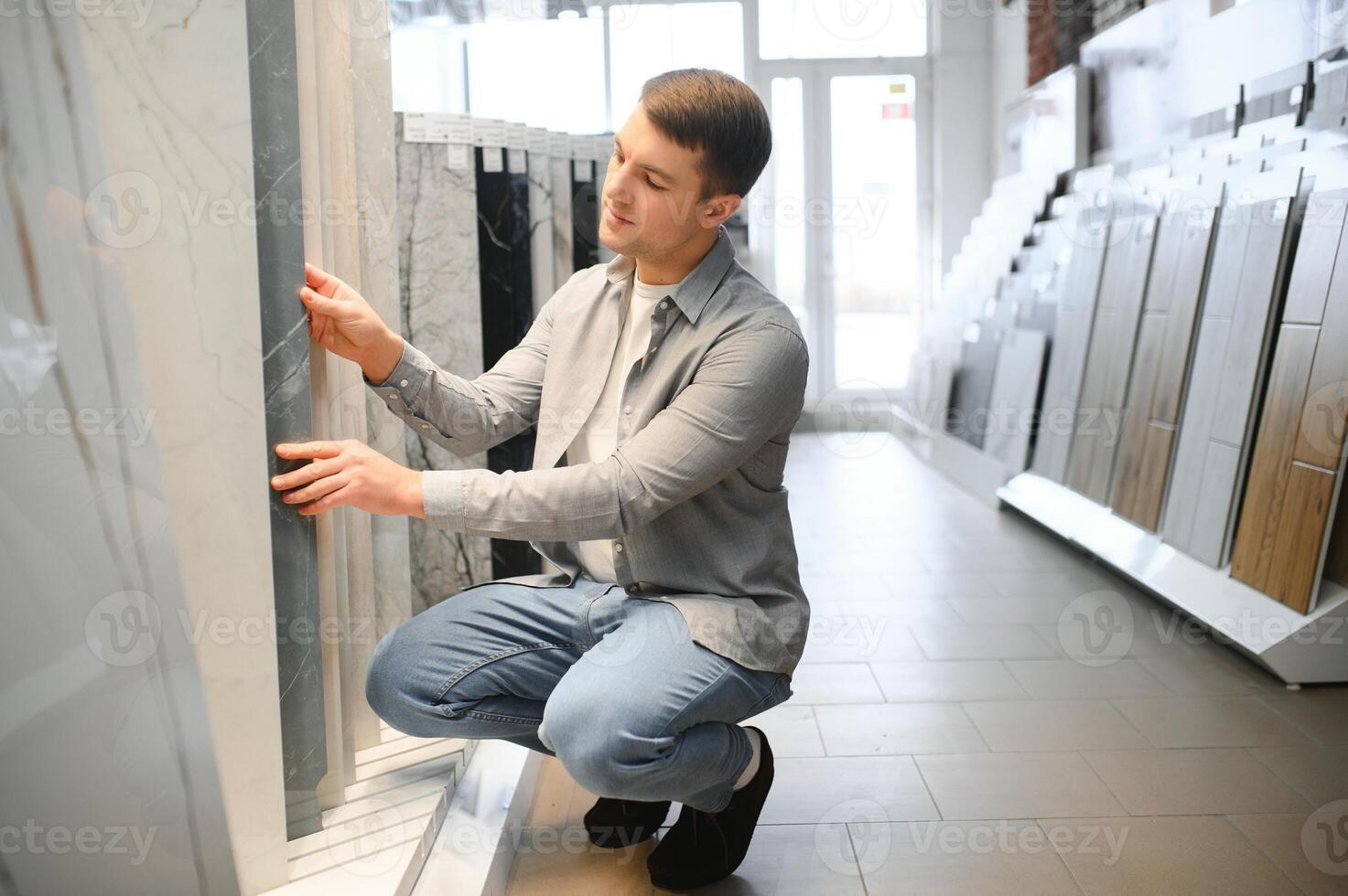 Male architect or interior designer choosing ceramic texture sample from swatch board in design studio photo