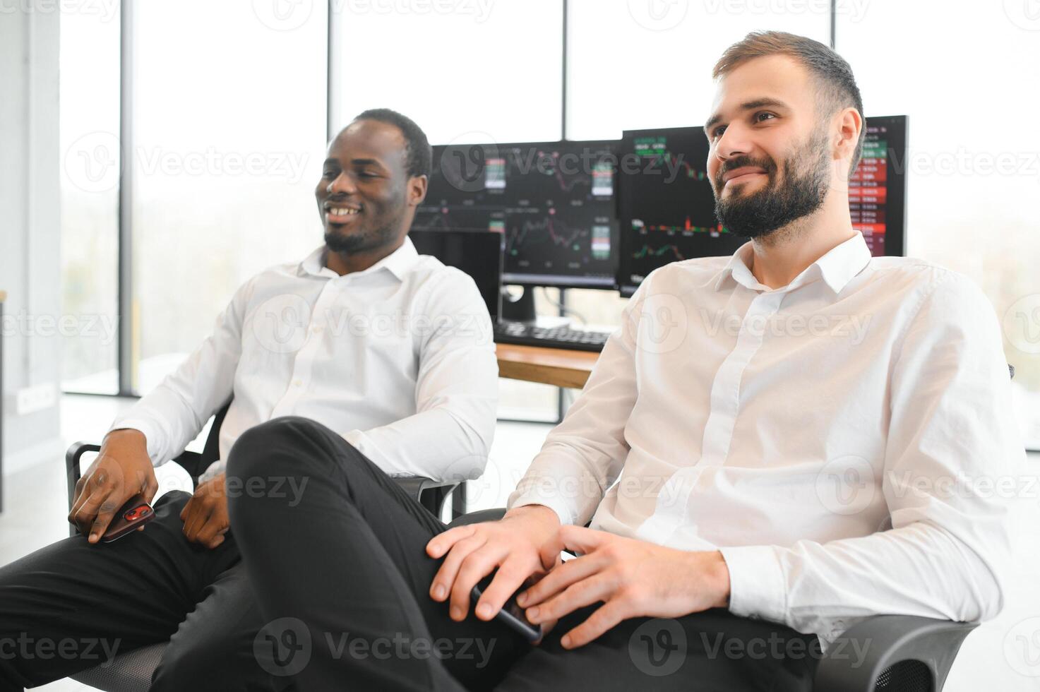 Two successful trader sitting in office, checking cryptocurrency information data on finance market graph, pointing on monitor photo