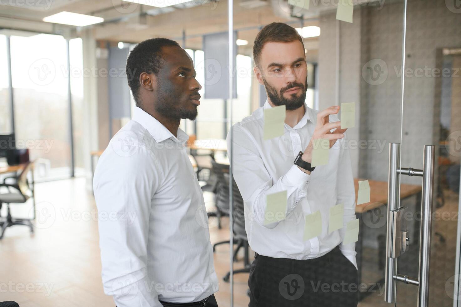 colleagues discuss and stick notes on the glass photo