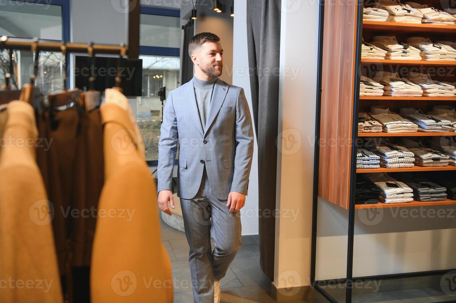 sale, shopping, fashion, style and people concept - elegant young man in suit in mall or clothing store photo
