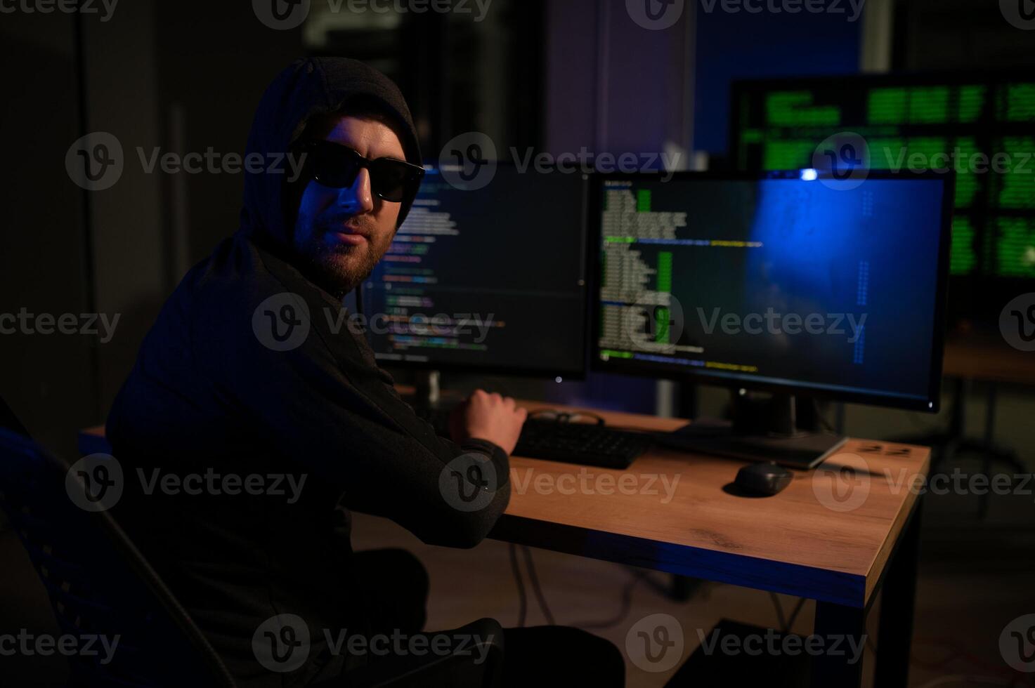 hacker sitting at desk in dark atmosphere. A computer programmer or hacker. Anonymous computer hacker. photo