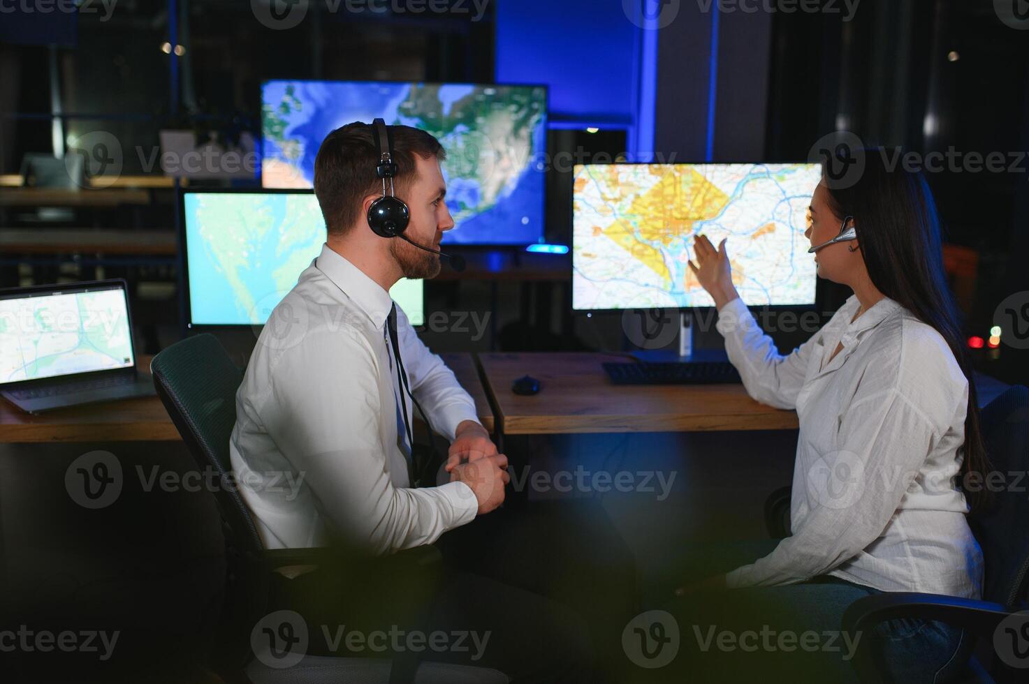 Center of dispatching maintenance. Portrait of cheerful woman and man working via headset microphone while sitting on navigation controller board photo