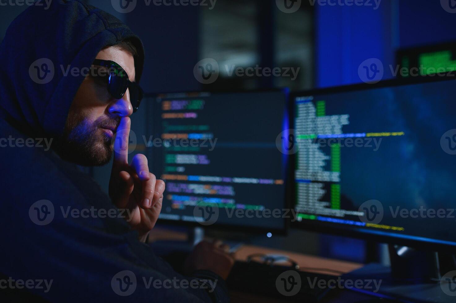 hacker sitting at desk in dark atmosphere. A computer programmer or hacker. Anonymous computer hacker. photo