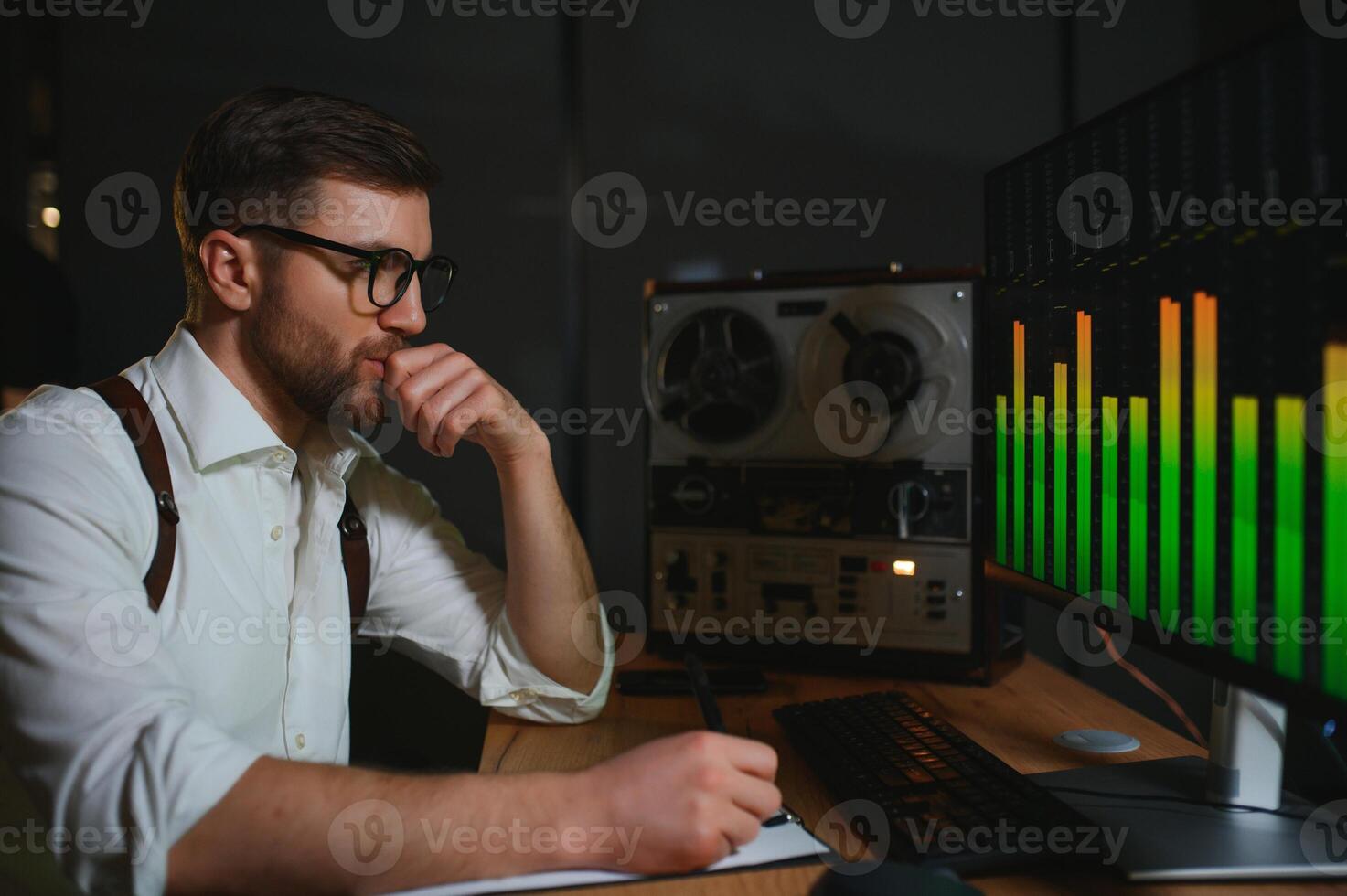 A male spy listens and records conversations on a reel-to-reel tape recorder photo