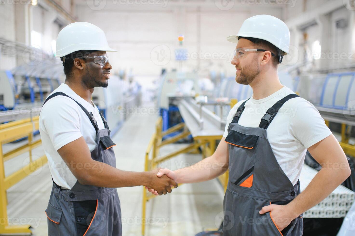 Two Diverse Professional Heavy Industry Engineers Wearing Safety Uniform and Hard Hats Working on Laptop photo