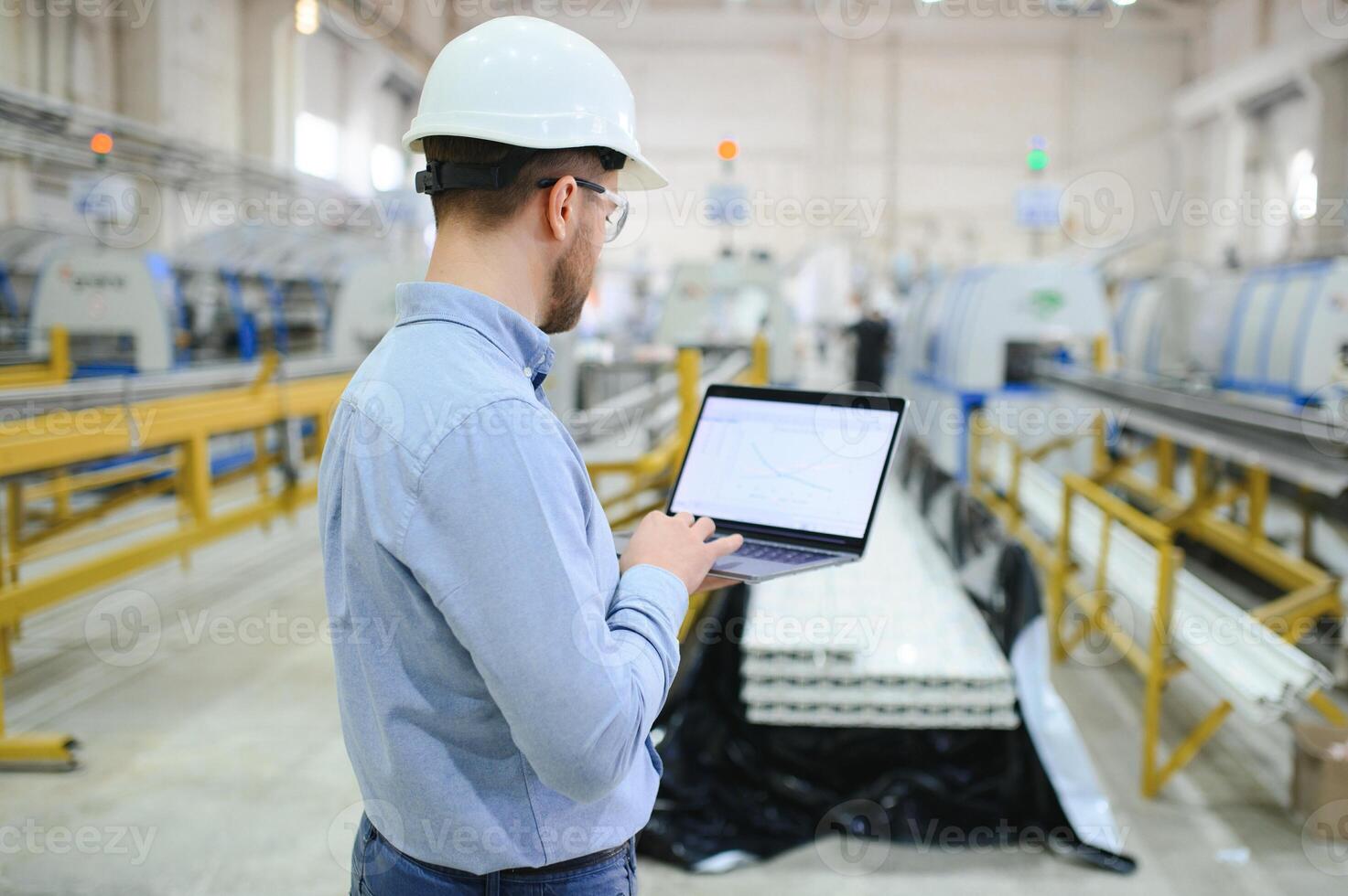 A young male engineer inspects the production of plastic window frames photo