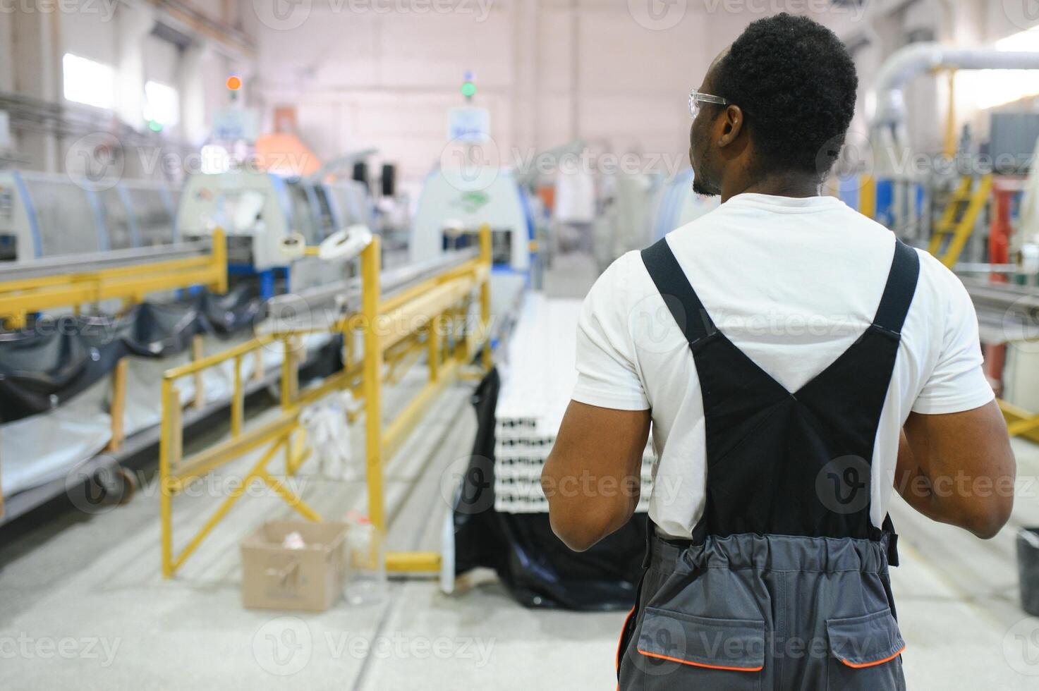 Industrial worker indoors in factory. Young technician with orange hard hat photo