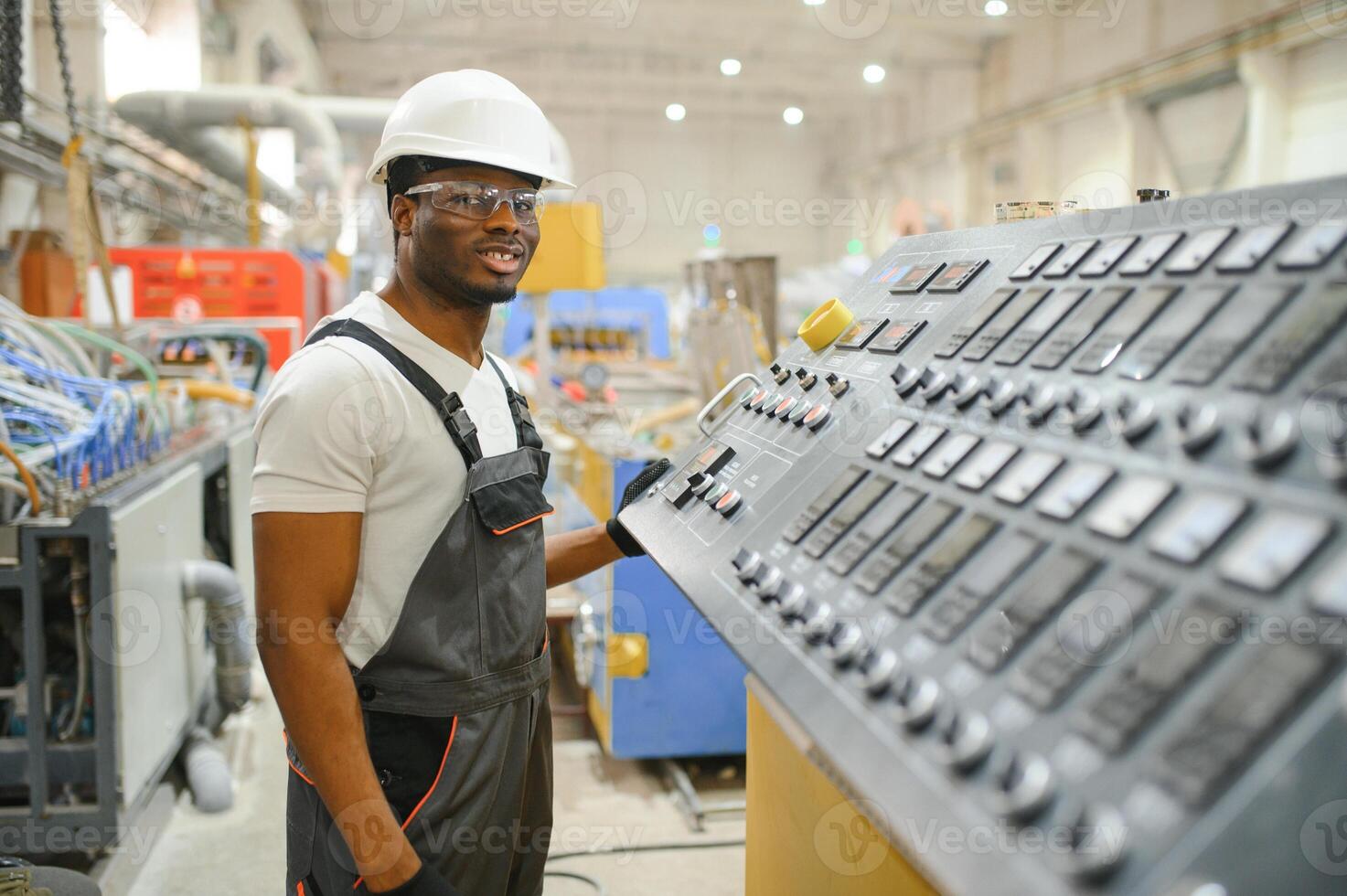 Portrait of African American male engineer in uniform and standing in industrial factory photo