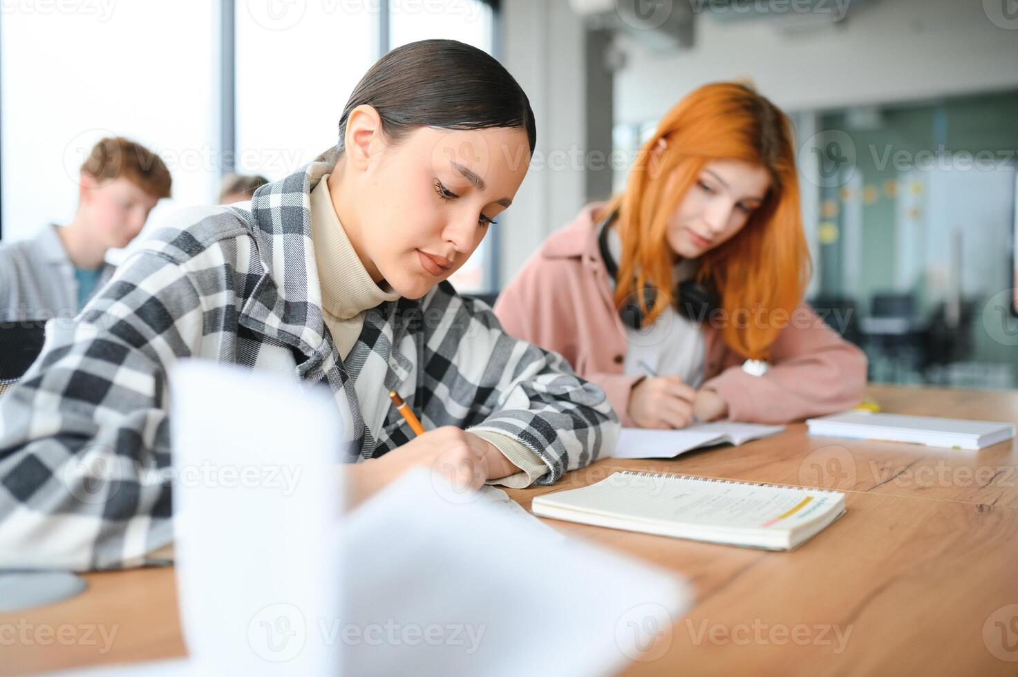 Testing. Closeup of young students sitting in a row and having test in their test-books photo