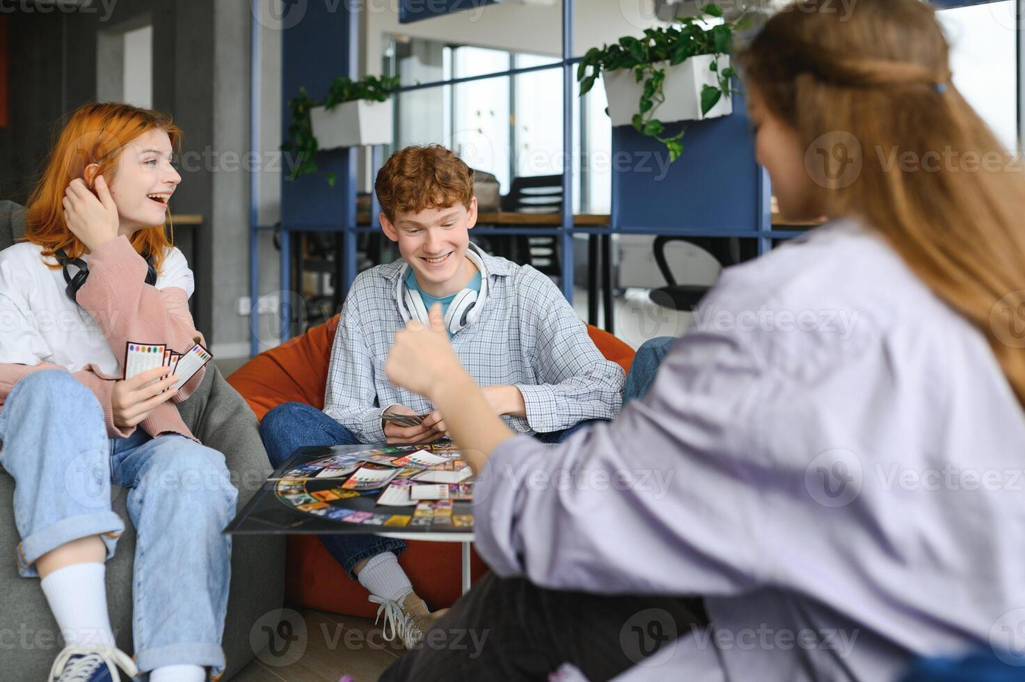 group of young friends playing board games together while sitting around table photo
