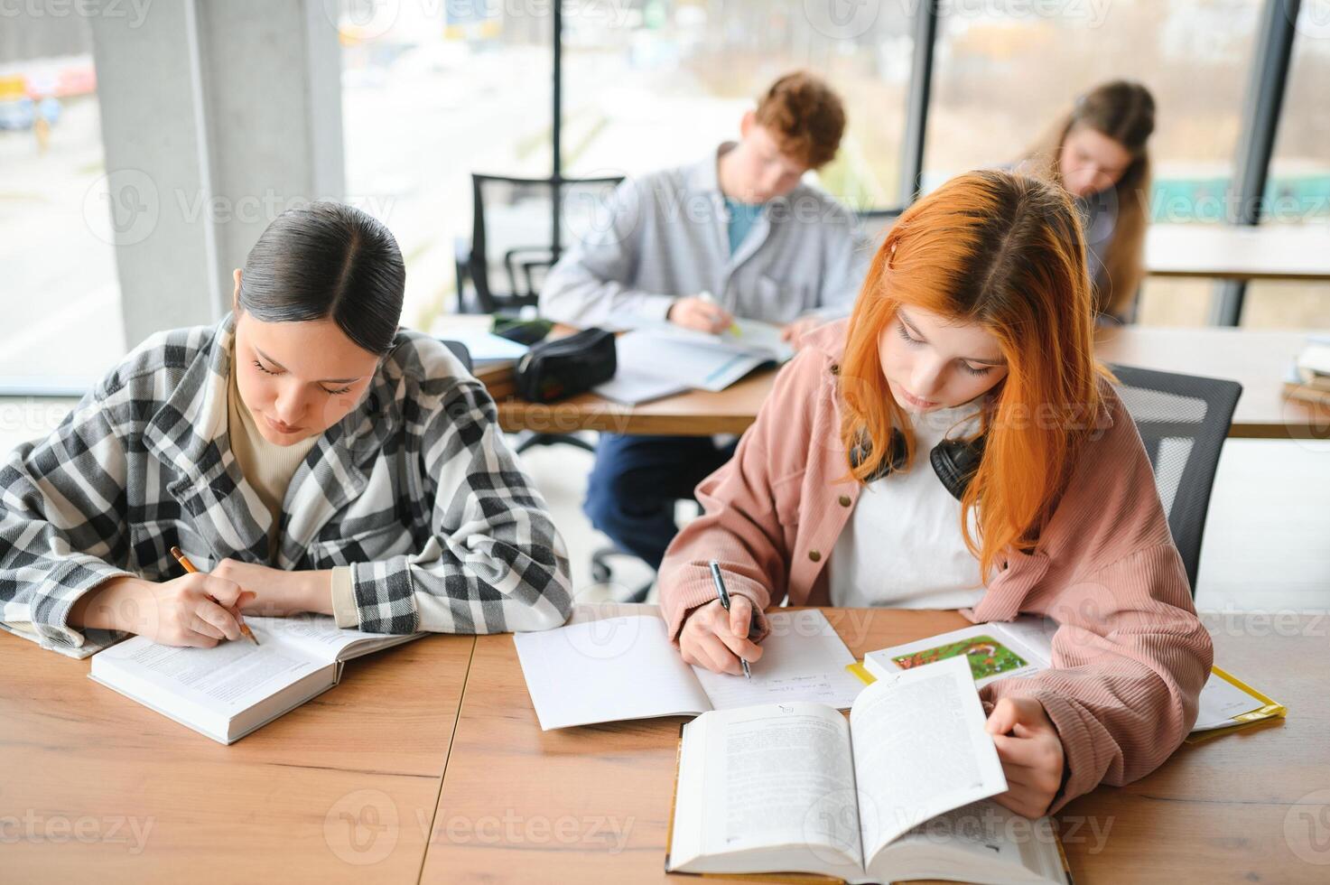students sit at shared desk making notes studying together at university photo