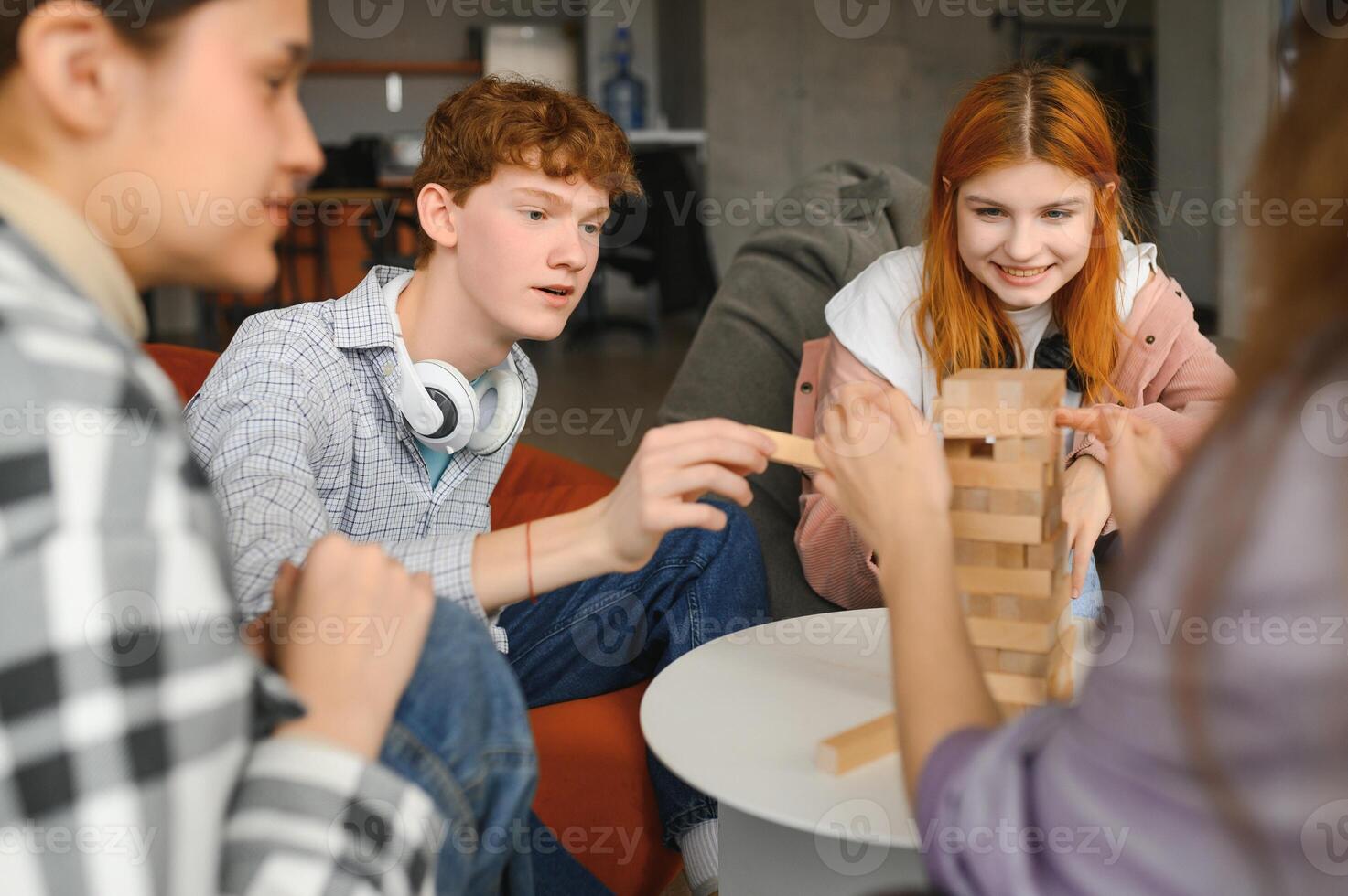 The company of young people plays a table game called jenga photo