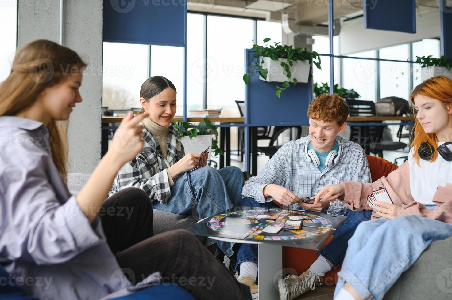 Group of creative friends sitting at wooden table. People having fun while playing board game photo