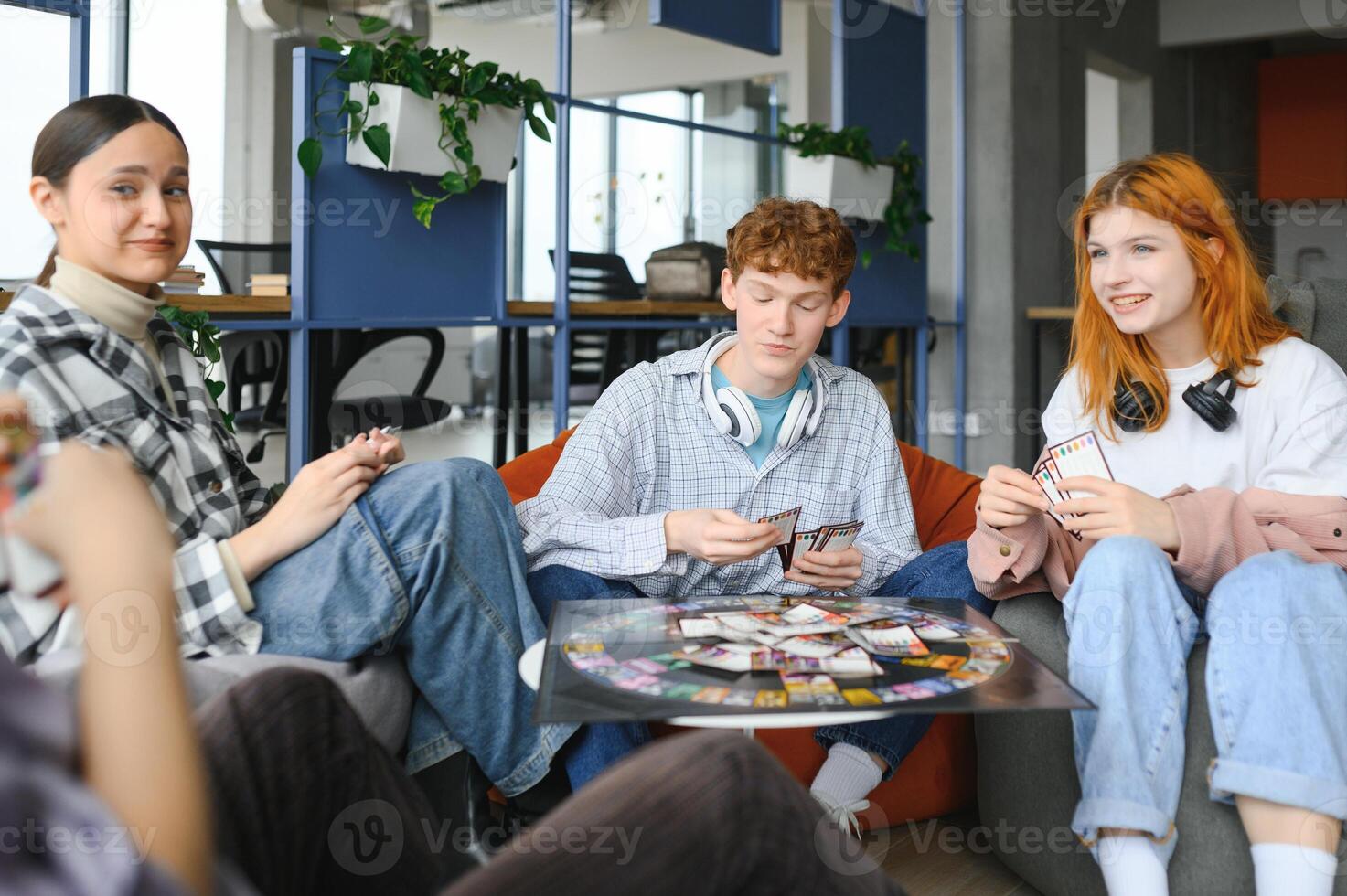 group of young friends playing board games together while sitting around table photo