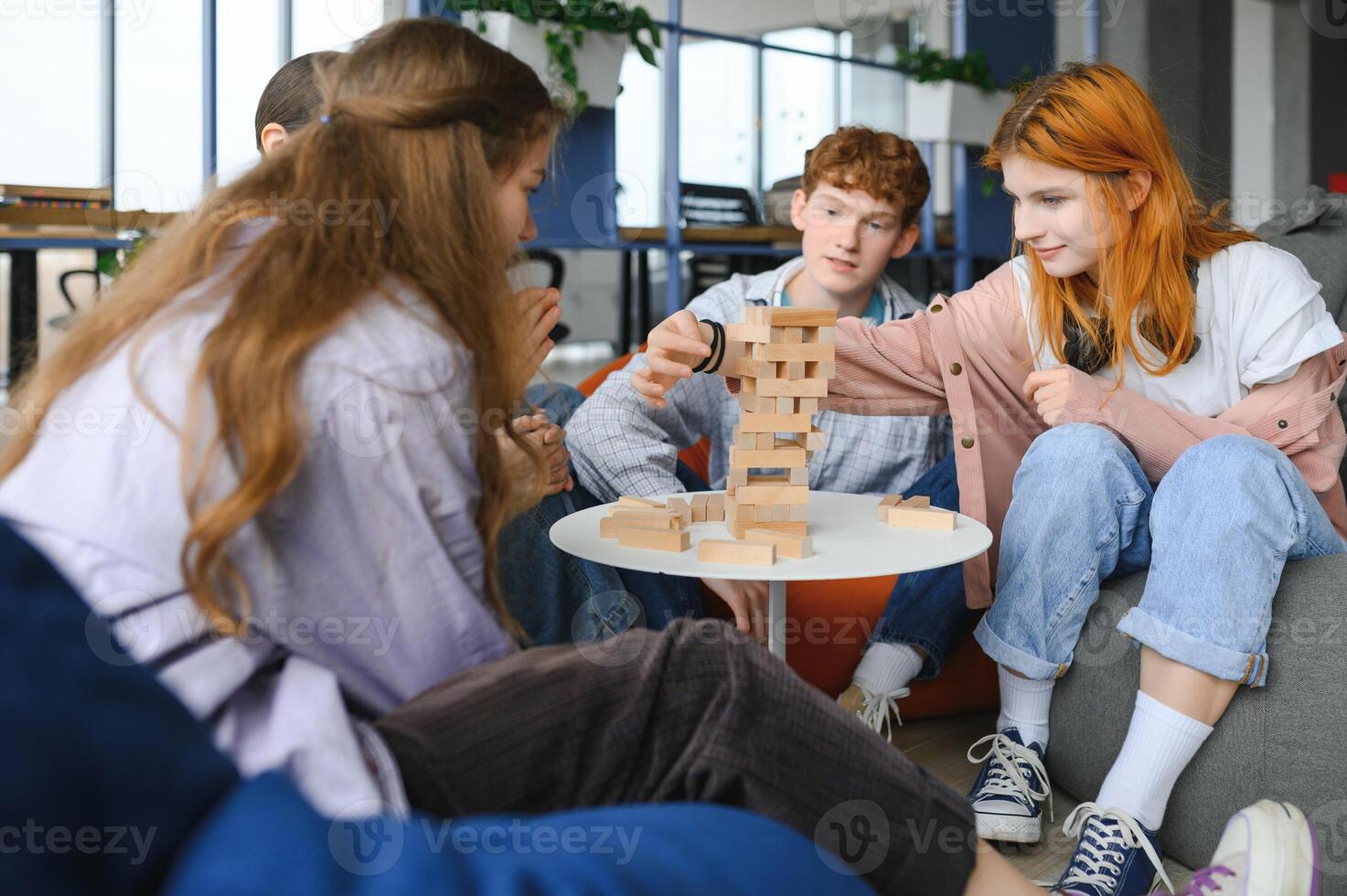 Group of creative friends sitting at wooden table. People having fun while playing board game photo