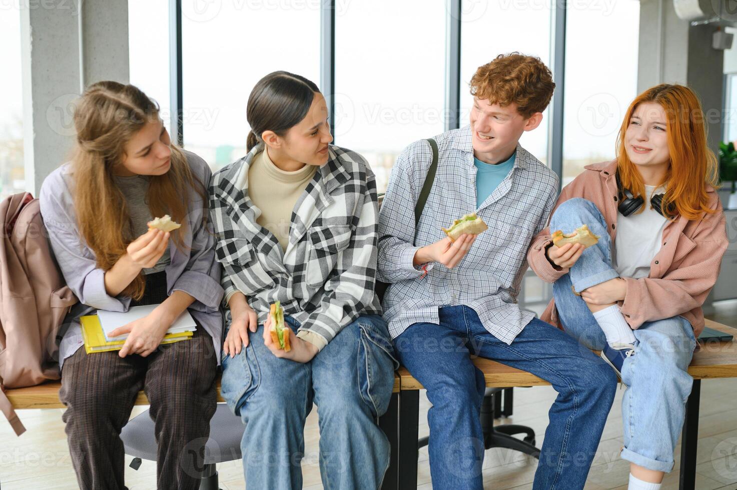 A group of young students having a lunch break together and eating sandwiches photo