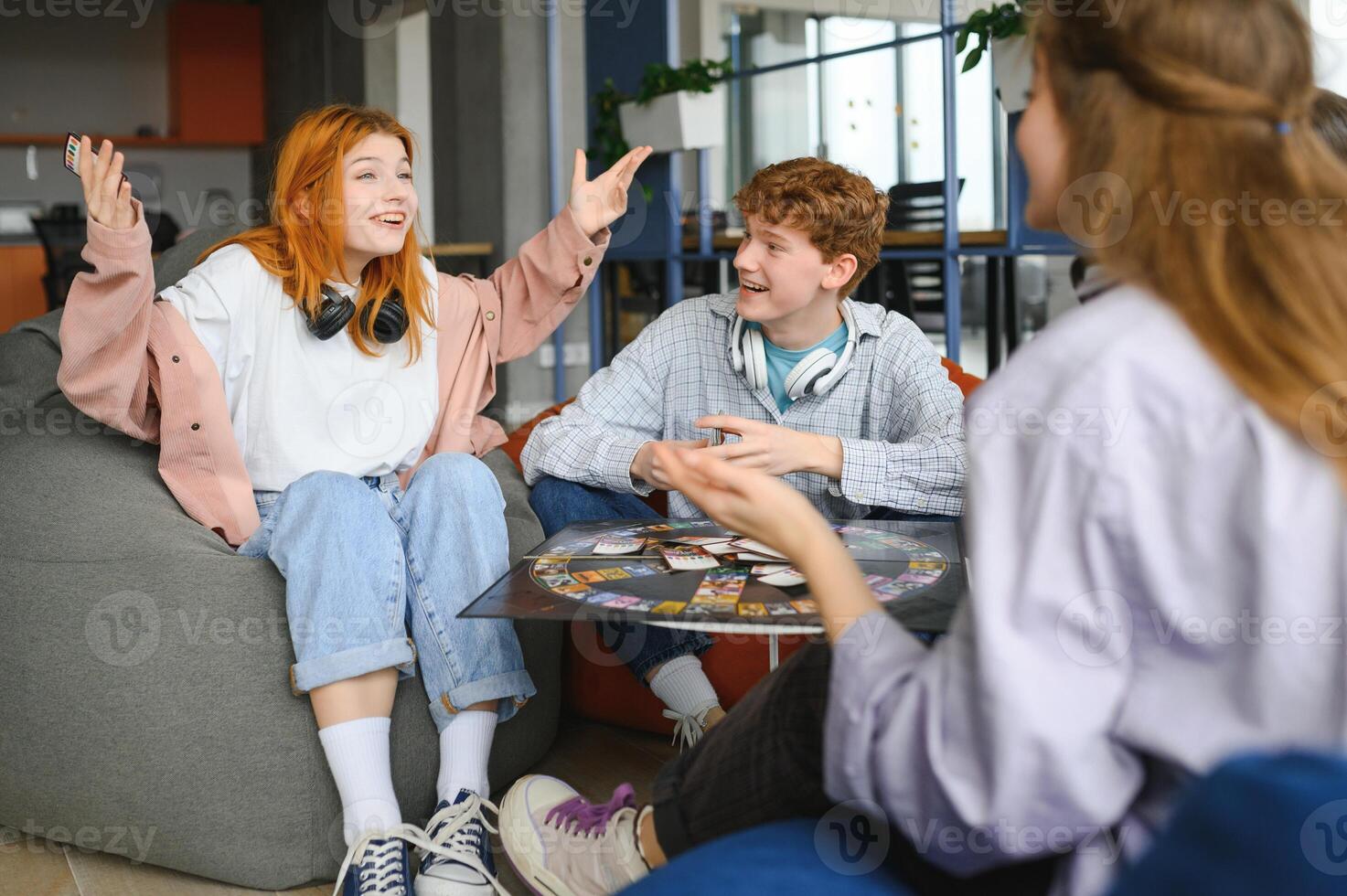 Group of creative friends sitting at wooden table. People having fun while playing board game photo