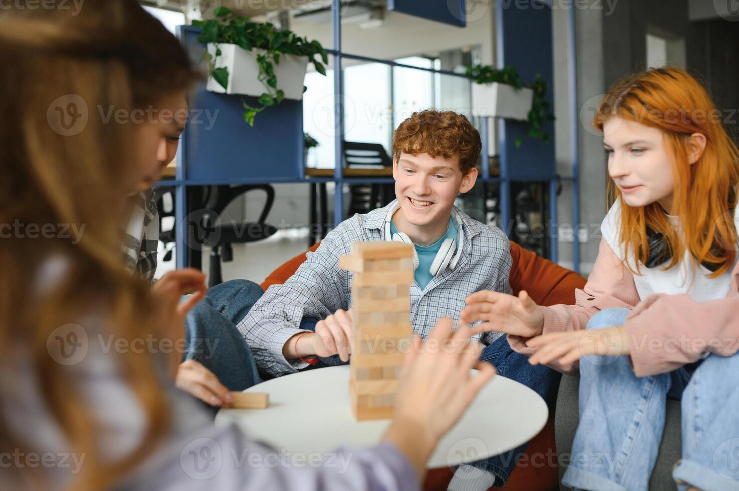 The company of young people plays a table game called jenga photo