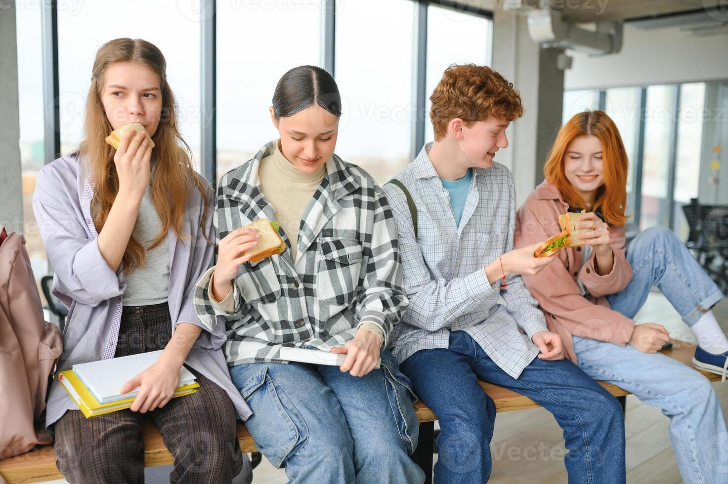 A group of young students having a lunch break together and eating sandwiches photo