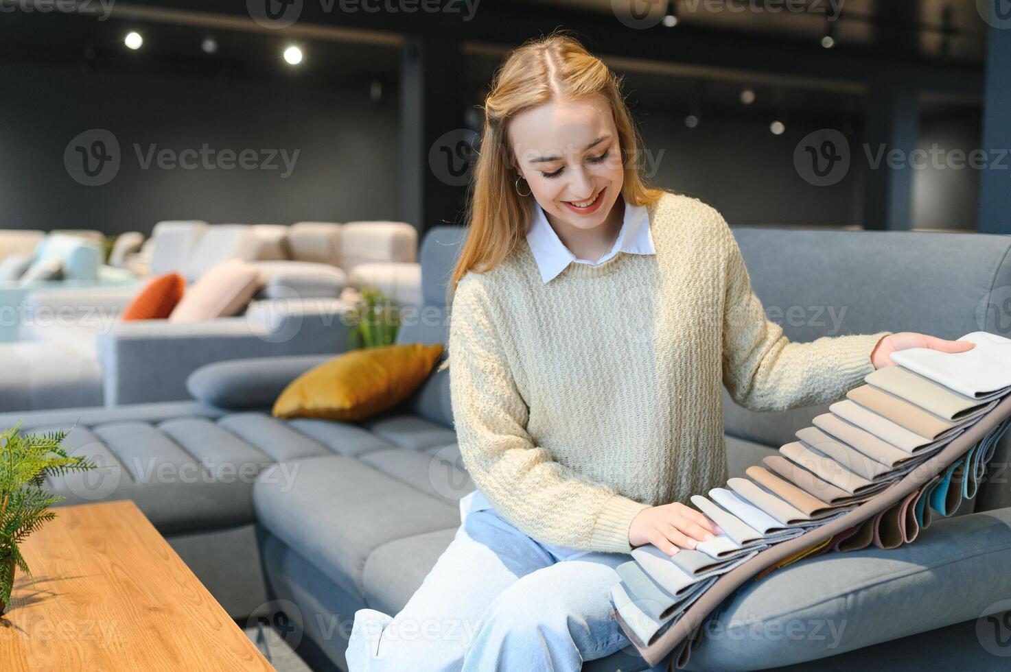 Happy young woman chooses sofa for home in furniture store photo