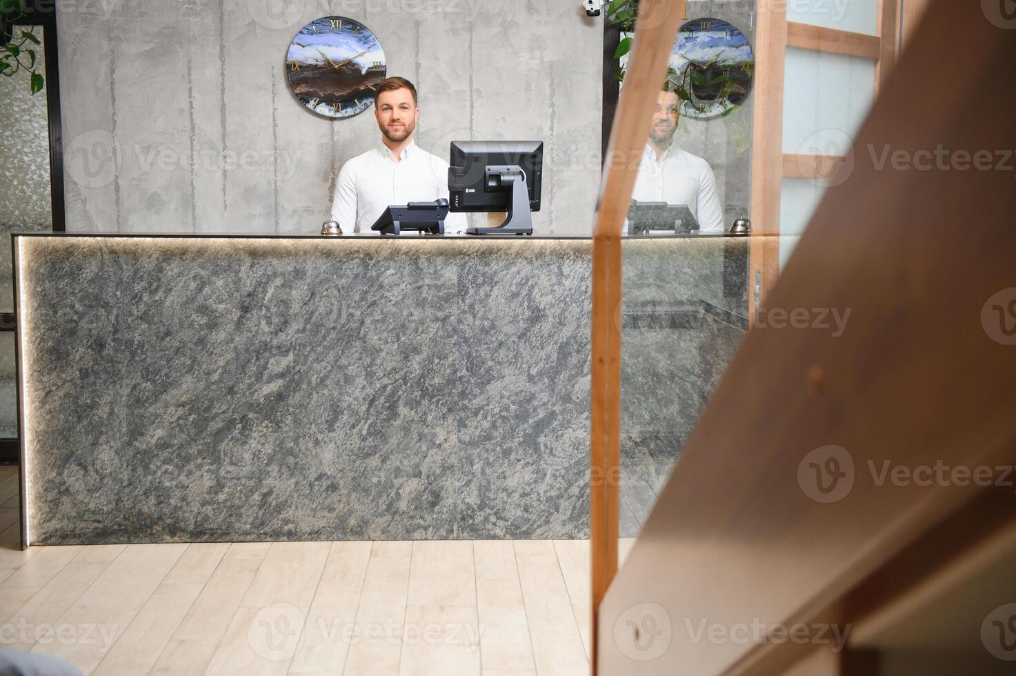 Portrait of a young male receptionist in a hotel lobby wearing a white shirt photo