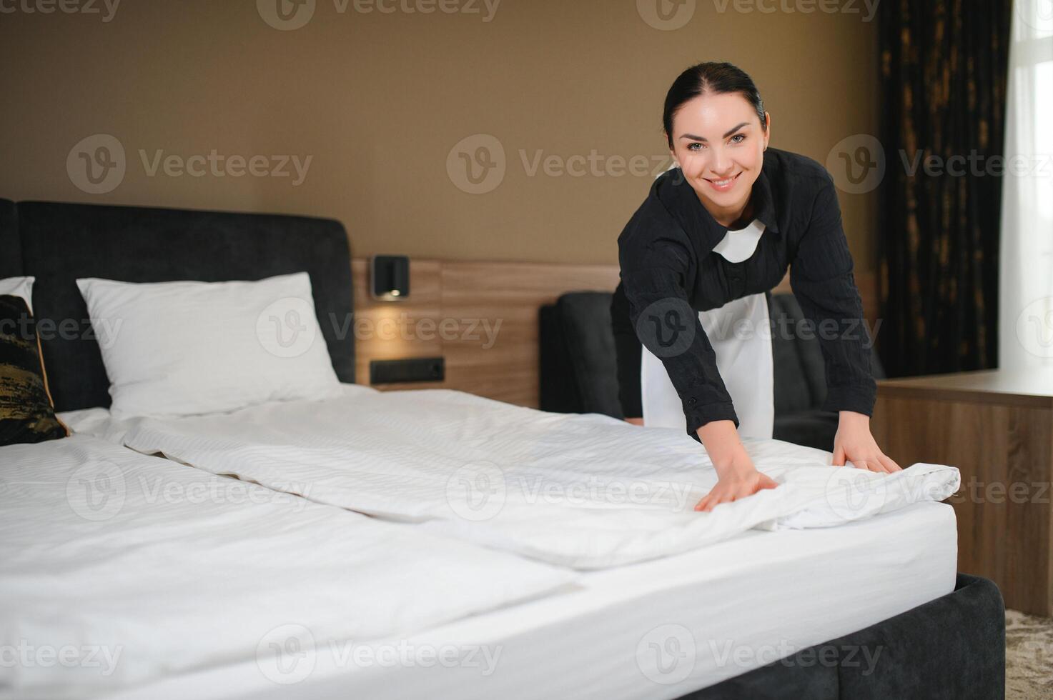 Young hotel maid making the bed photo