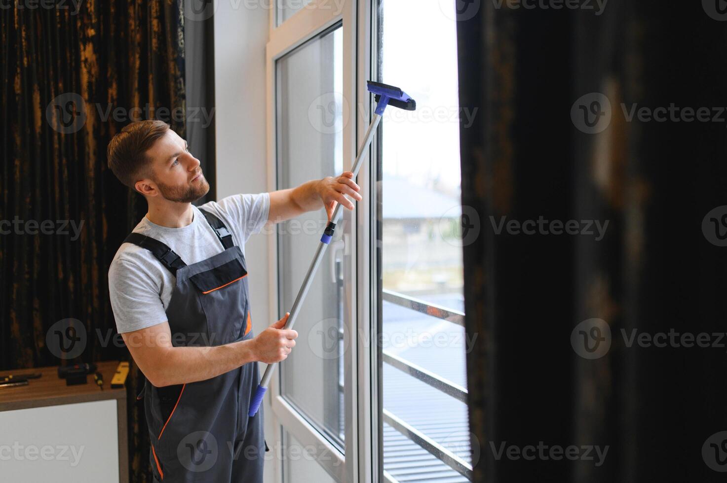 Male professional cleaning service worker in overalls cleans the windows and shop windows of a store with special equipment photo