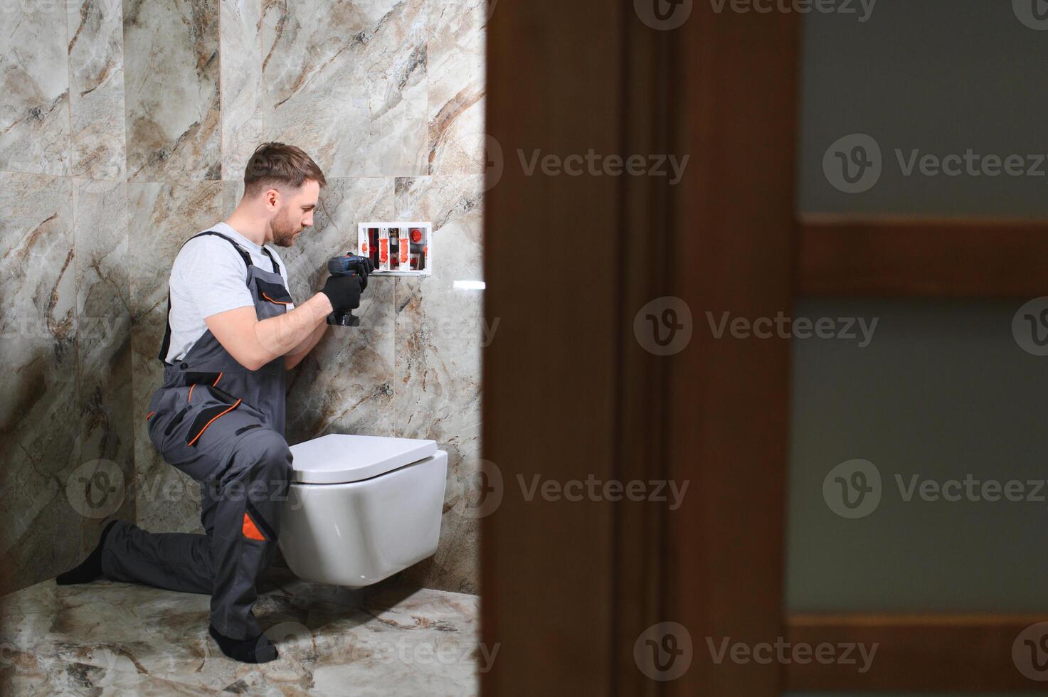 Plumber installing toilet in restroom photo