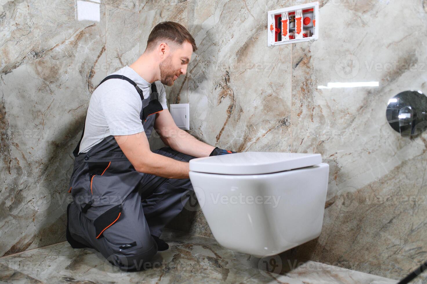 Plumber installing toilet in restroom photo