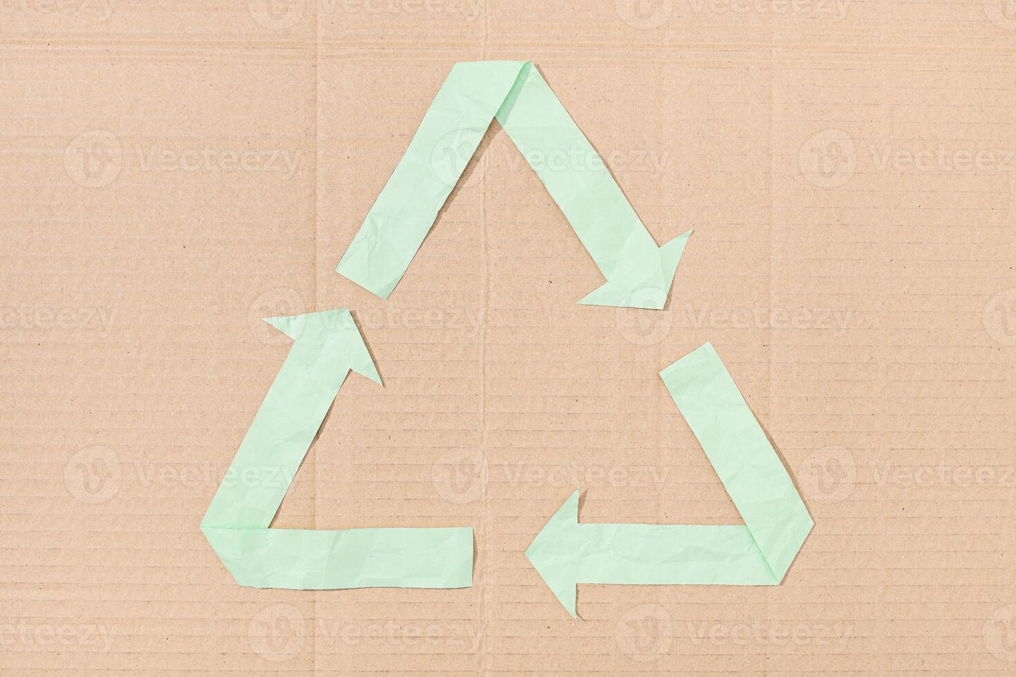 Recycle symbol made of paper cut on cardboard background texture photo