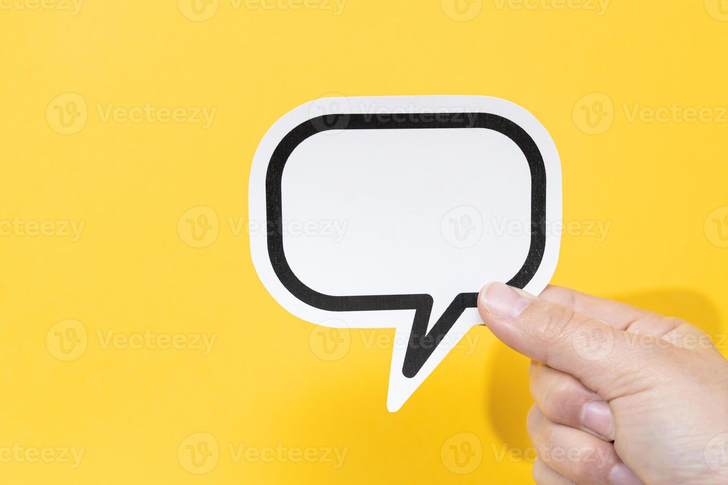Hand holding a blank speech bubble isolated on yellow background. Template Mockup photo