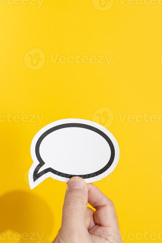 Hand holding a blank speech bubble isolated on yellow background. Template Mockup photo