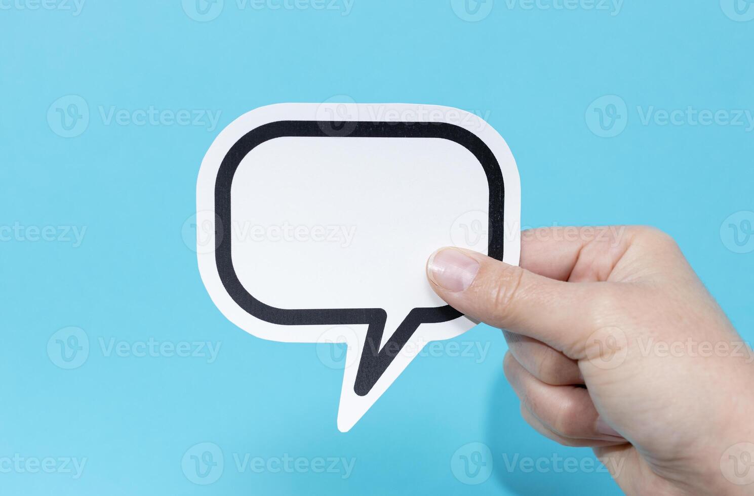 Hand holding a blank speech bubble isolated on blue background. Template Mockup photo