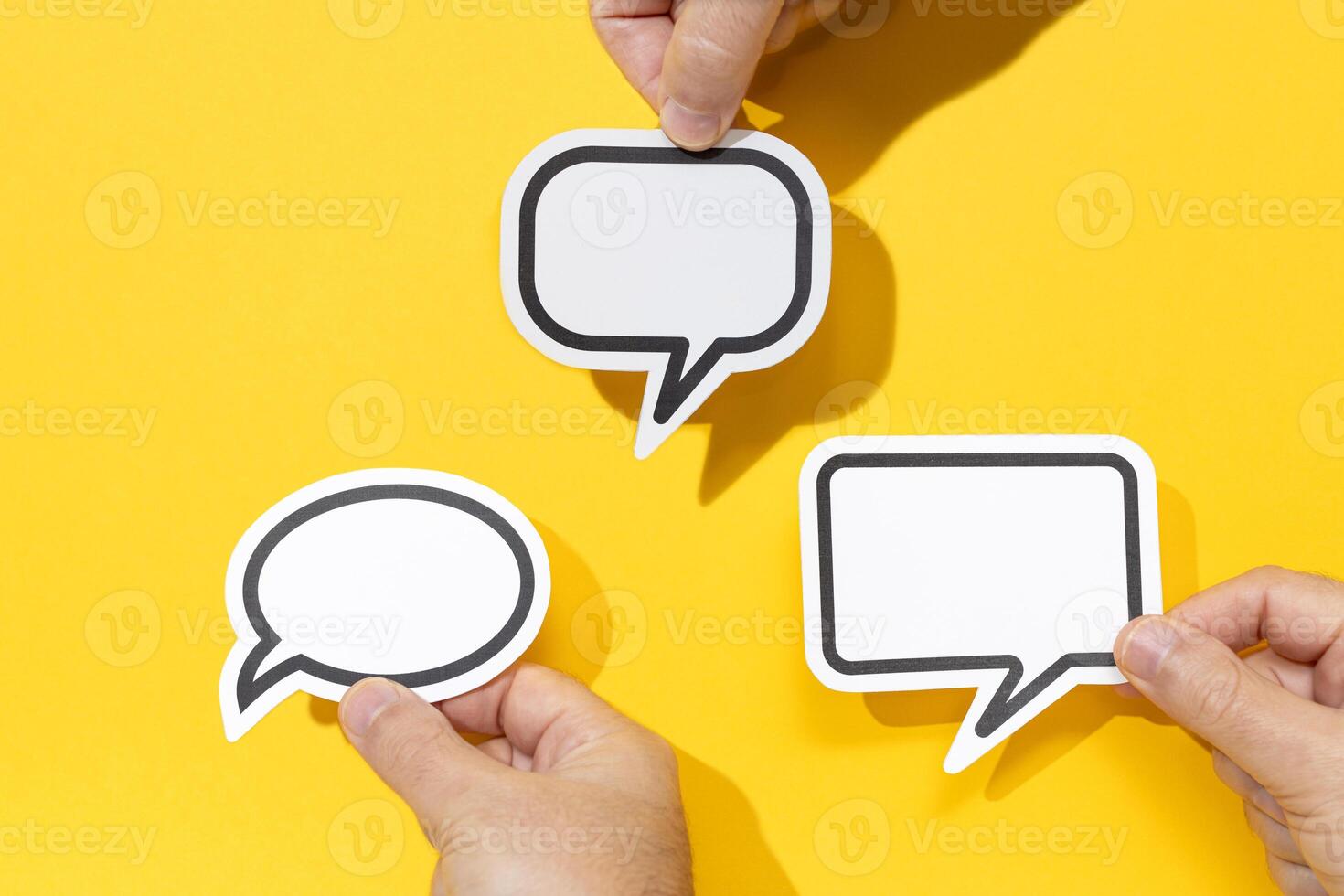 Group of three hands holding a Blank Speech Bubble isolated on yellow background. Mock up template photo
