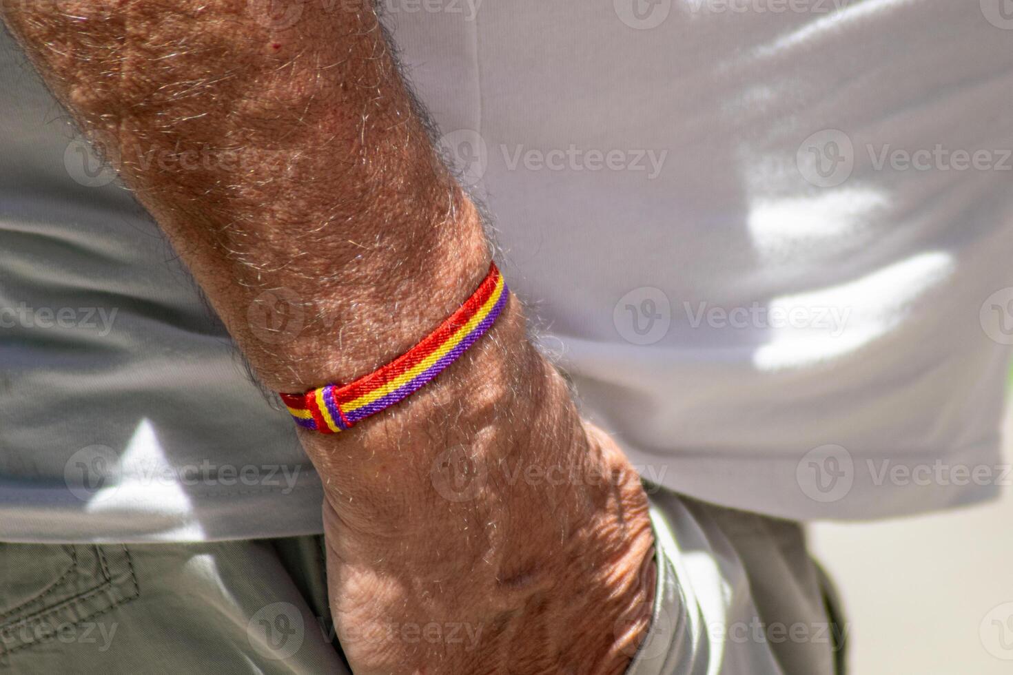 close-up view of a wristband with the colors of the Spanish republic flag on the wrist of an senior man photo